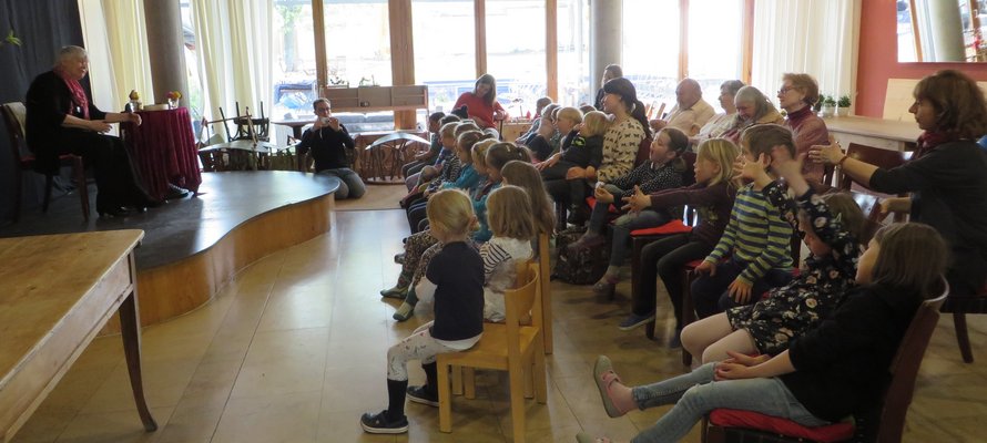 Menschen sitzen in einem Saal und hören einer Person zu.