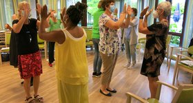 Inhouse-Schulung im Altenburgheim Frauen stehen sich paarweise gegenüber und klatschen sich gegenseitig mit den Händen ab