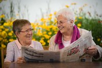 Zwei Seniorinnen lesen zusammen Zeitung.