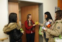 Jüngere Frauen bringen einer Seniorin Lebensmittel an ihre Haustüre.