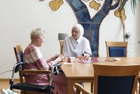 Zwei Seniorinnen sitzen am Tisch und spielen ein Brettspiel