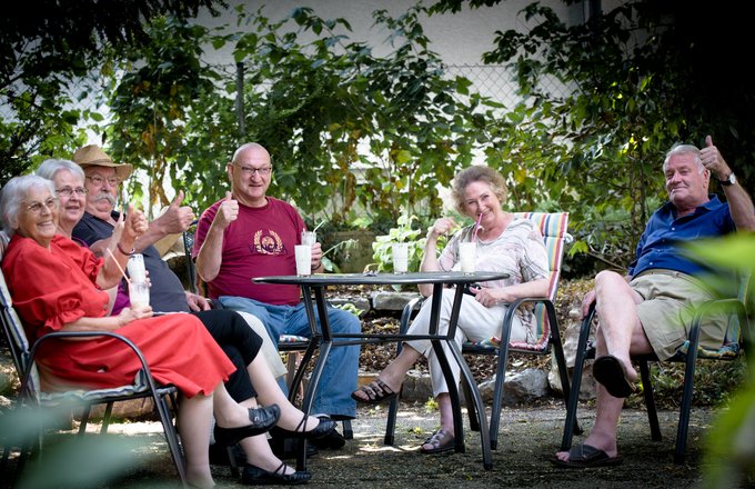 Fröhliche Seniorengruppe sitzt auf der Terrasse des Hauses
