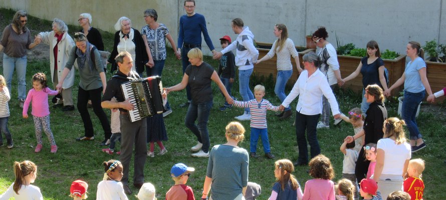 Kinder und Erwachsene tanzen zusammen im Garten.