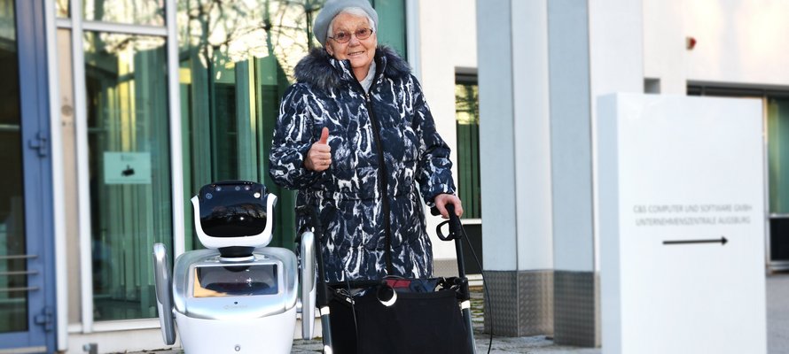 Roboter NIKA neben einer Seniorin mit Rollator