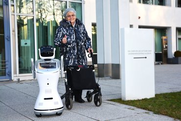 Roboter NIKA neben einer Seniorin mit Rollator