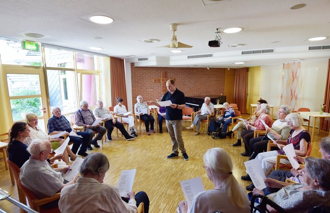 Senioren sitzen im Kreis und singen.